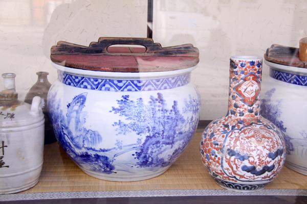 店頭ガラス面に飾られている一宝の「醤油甕」。美しい模様が描かれた陶器製の甕です。実用性と芸術性を兼ね備えた逸品ですので、是非ご覧下さい♪の画像