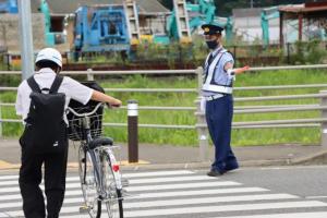 横断歩道を渡る学生と交通指導をする誠一さんの写真