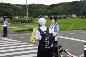横断歩道を渡る学生と交通指導をするふうかさんの写真