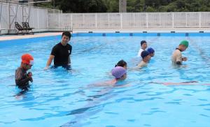 着衣でプールの中を歩く子どもたちの写真