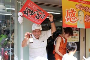 おせったいの特典を手に笑顔を覗かせる男性