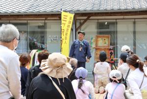 紙芝居を披露している三ツ沢さんと聞き入っている来場者の写真
