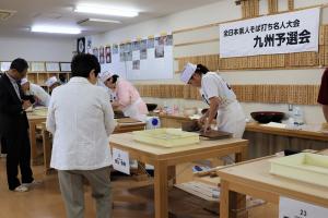 そばを切っている出場者とチェックしている審査員の写真