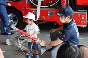消防車の放水ホースを触らせてもらっている子どもの写真