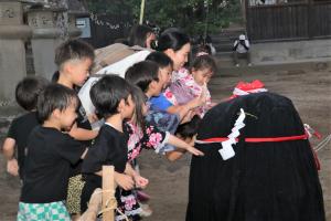 座りこんだ張り子の牛を触る子どもたち