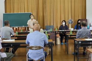 あいさつをしているいなみ事務局長と聞いている参加者たちの写真