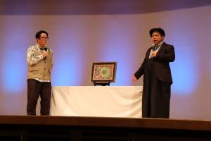 司会者とジミー大西さんがアートを前に話している写真