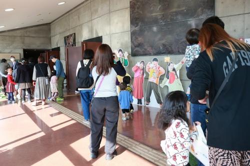 ホール前の写真パネルの前で写真をとっている来場者の写真