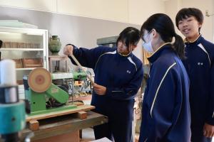 グラインダーでまさかりを成形している生徒たちの写真