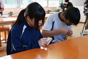 カッターナイフでまさかりを成形している生徒たちの写真