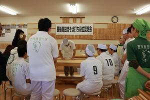 そば打ちをしている師範代とそれをみて学んでいる受験者たちの写真
