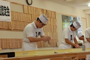 試験に挑んでいる高田高校そば打ちチームの高校生たちの写真