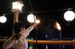 大たいまつに点火するために矢を射る写真