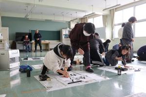 指導を受けながら書き初めにとりくむ児童たちの写真