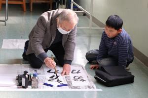 地域の方にお手本を見せてもらっている児童の写真