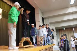 石橋の木製模型に乗って構造や仕組みを学ぶ子どもたちの写真