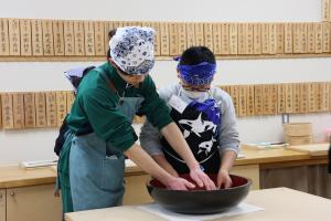 高校生といっしょにそばをこねている小学生の写真