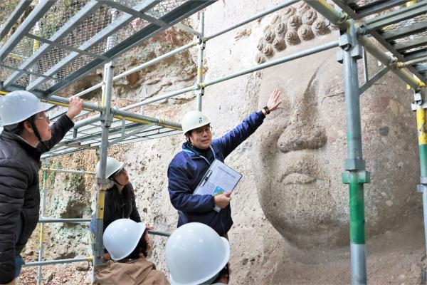 摩崖仏の説明をする担当者