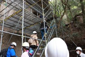 ヘルメットを着けて足場を上る参加者