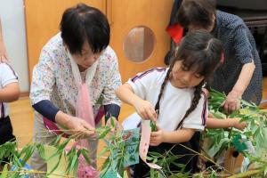七夕の飾り付けをする園児と老人クラブの方の様子