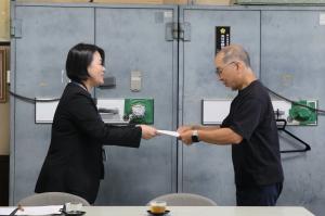 学校教育課長が青木さんへ委嘱状を手渡している写真