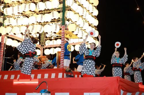 草地踊り保存会の踊り披露、踊り子たちが両手を挙げている踊りの写真