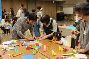 おりがみをして遊ぶ子どもたちと愛育会員の方々の写真