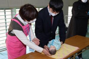 実物大の新生児の人形を抱き方を教わる生徒